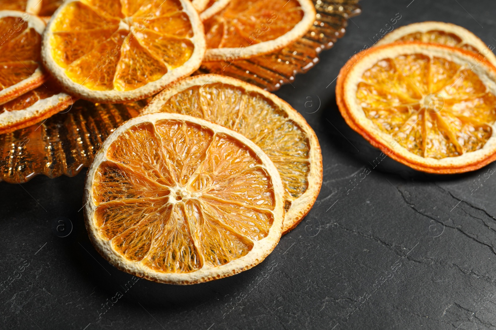 Photo of Dry orange slices on black table, closeup