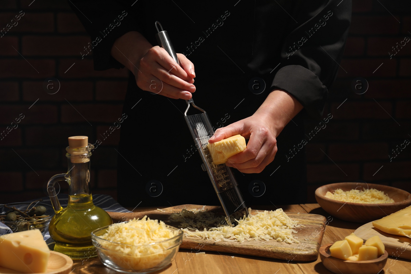 Photo of Woman grating cheese at wooden table, closeup