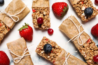 Tasty granola bars and ingredients on white table, flat lay