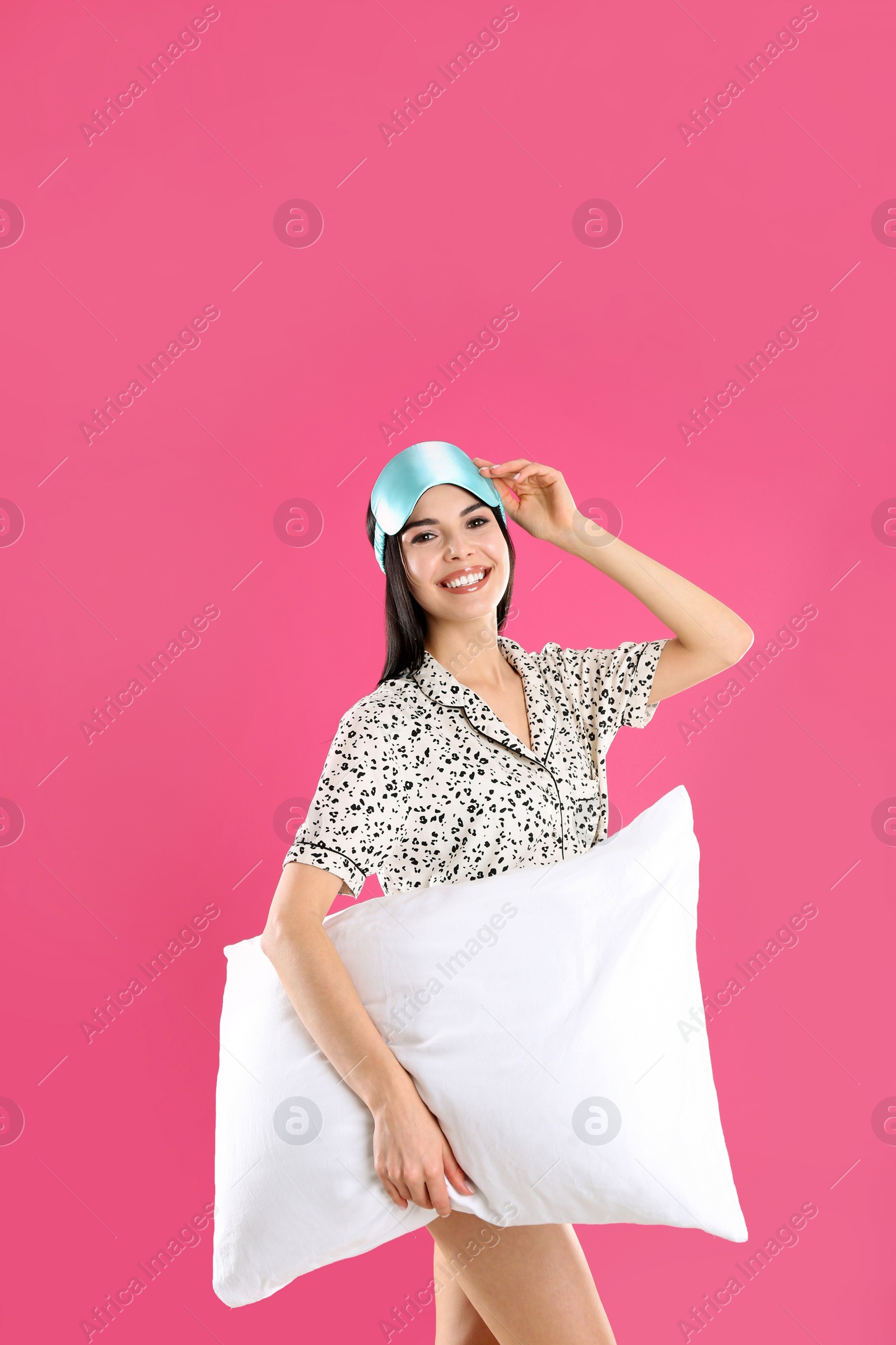 Photo of Young woman with pillow and sleep mask on pink background