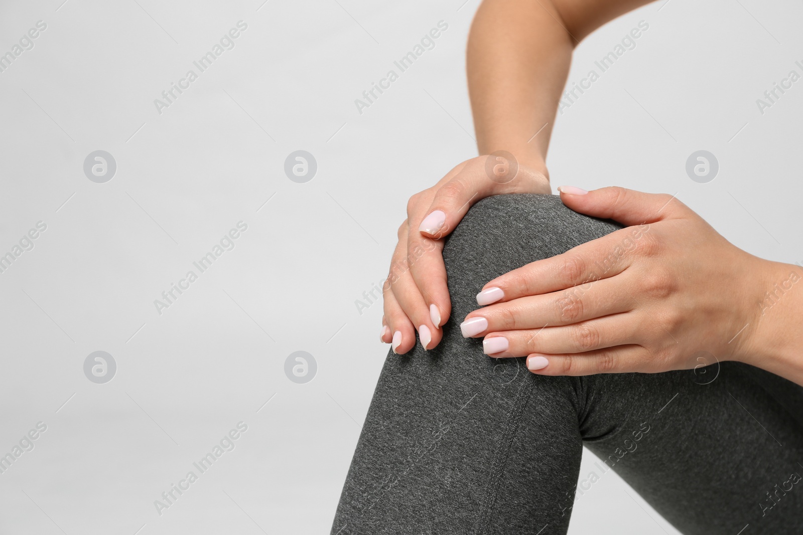 Photo of Woman having knee problems on grey background, closeup