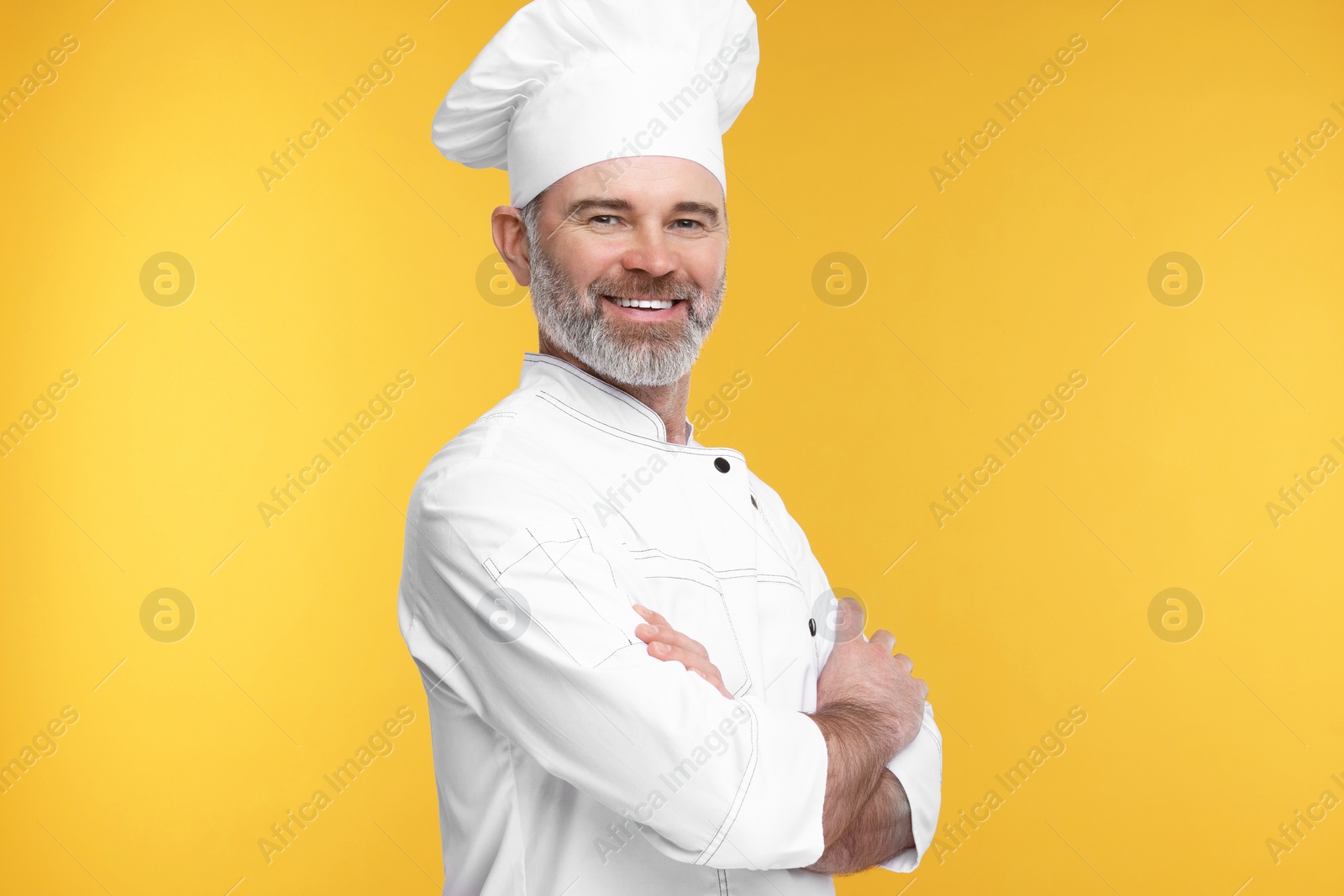 Photo of Happy chef in uniform on orange background