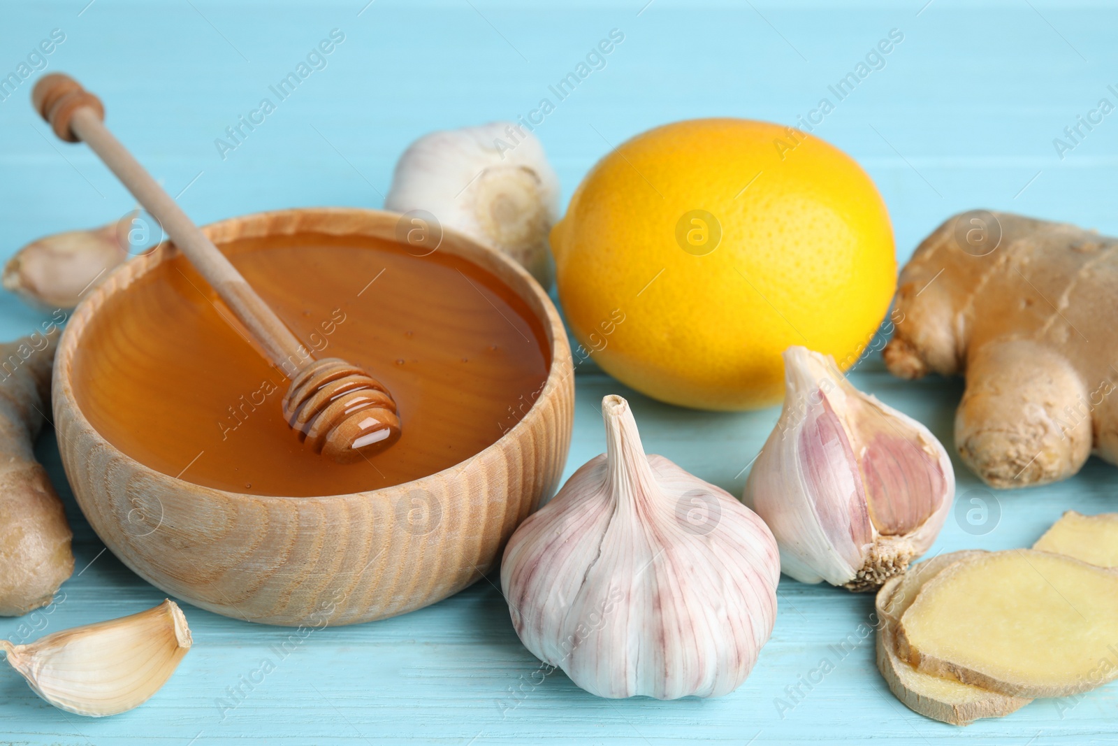 Photo of Fresh garlic and other natural cold remedies on light blue wooden table