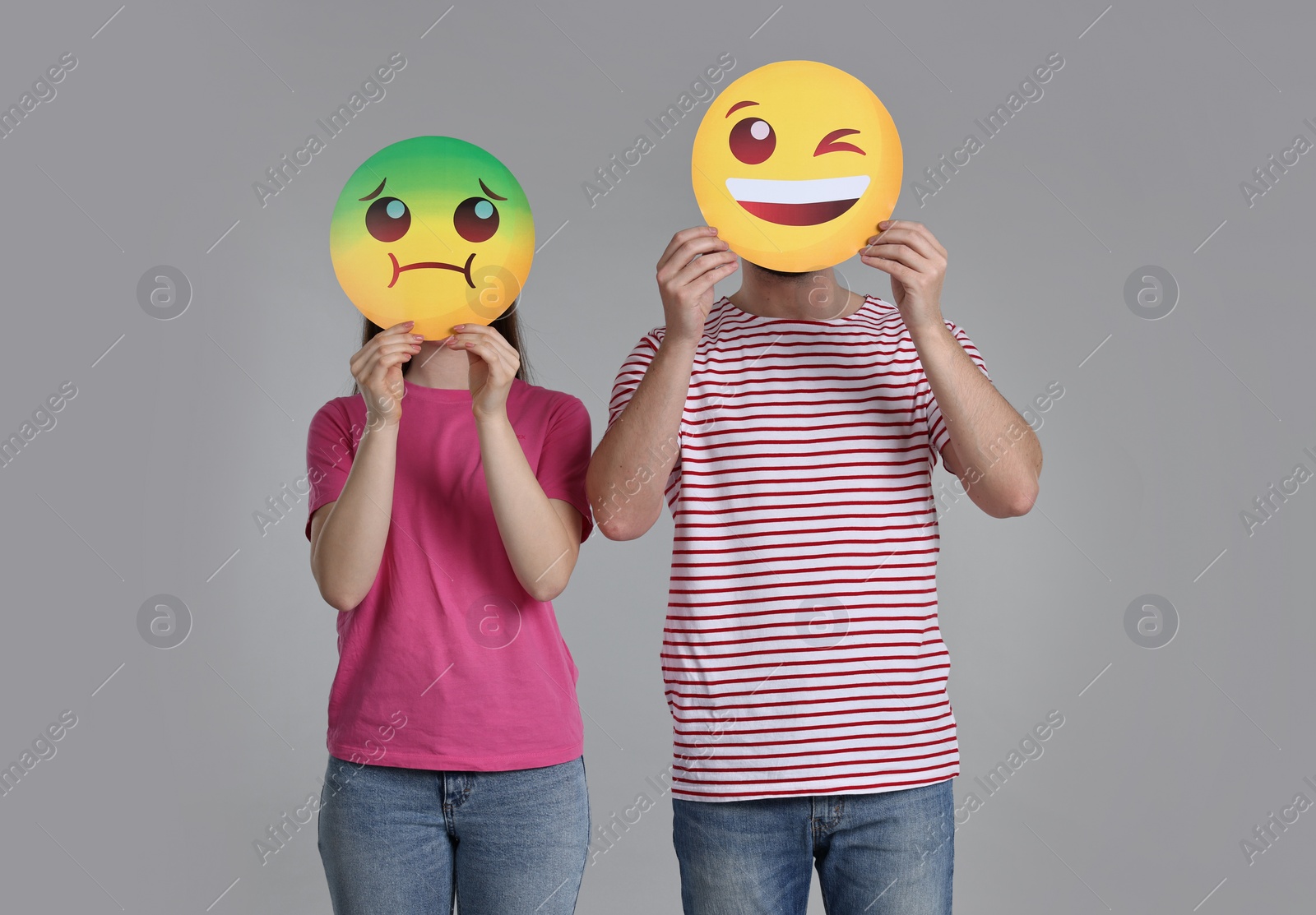 Photo of People covering faces with emoticons on grey background