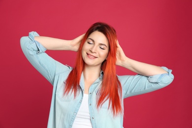 Photo of Young woman with bright dyed hair on red background
