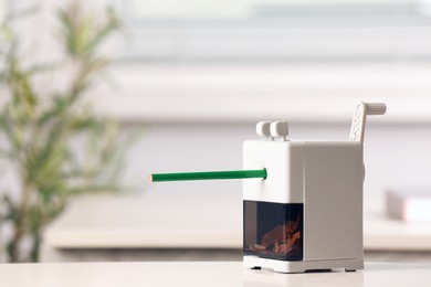 Mechanical sharpener with pencil on white table indoors. Space for text