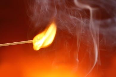 Photo of Burning matchstick on color background, closeup. Space for text