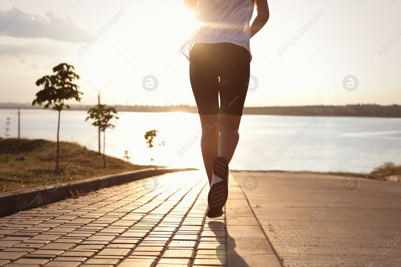 Photo of Young woman running near river in morning, closeup