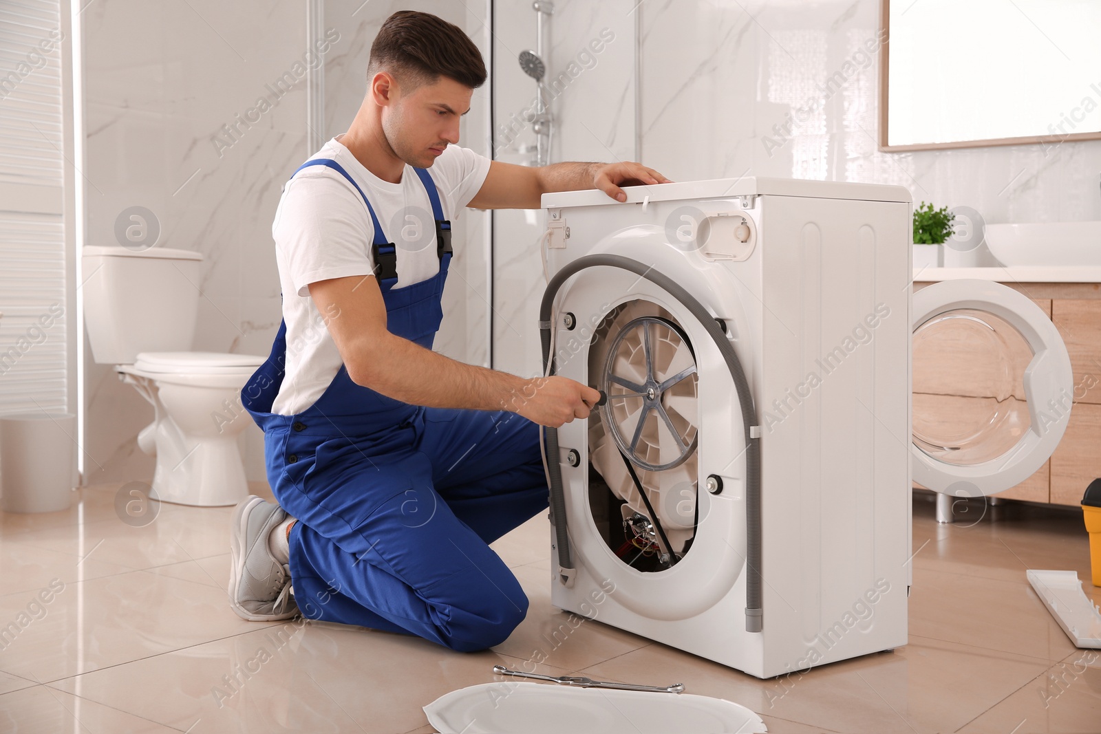 Photo of Professional plumber repairing washing machine in bathroom