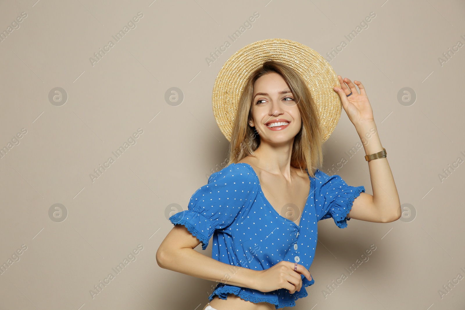 Photo of Beautiful young woman wearing straw hat on beige background, space for text. Stylish headdress