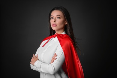 Photo of Confident businesswoman wearing superhero cape on grey background