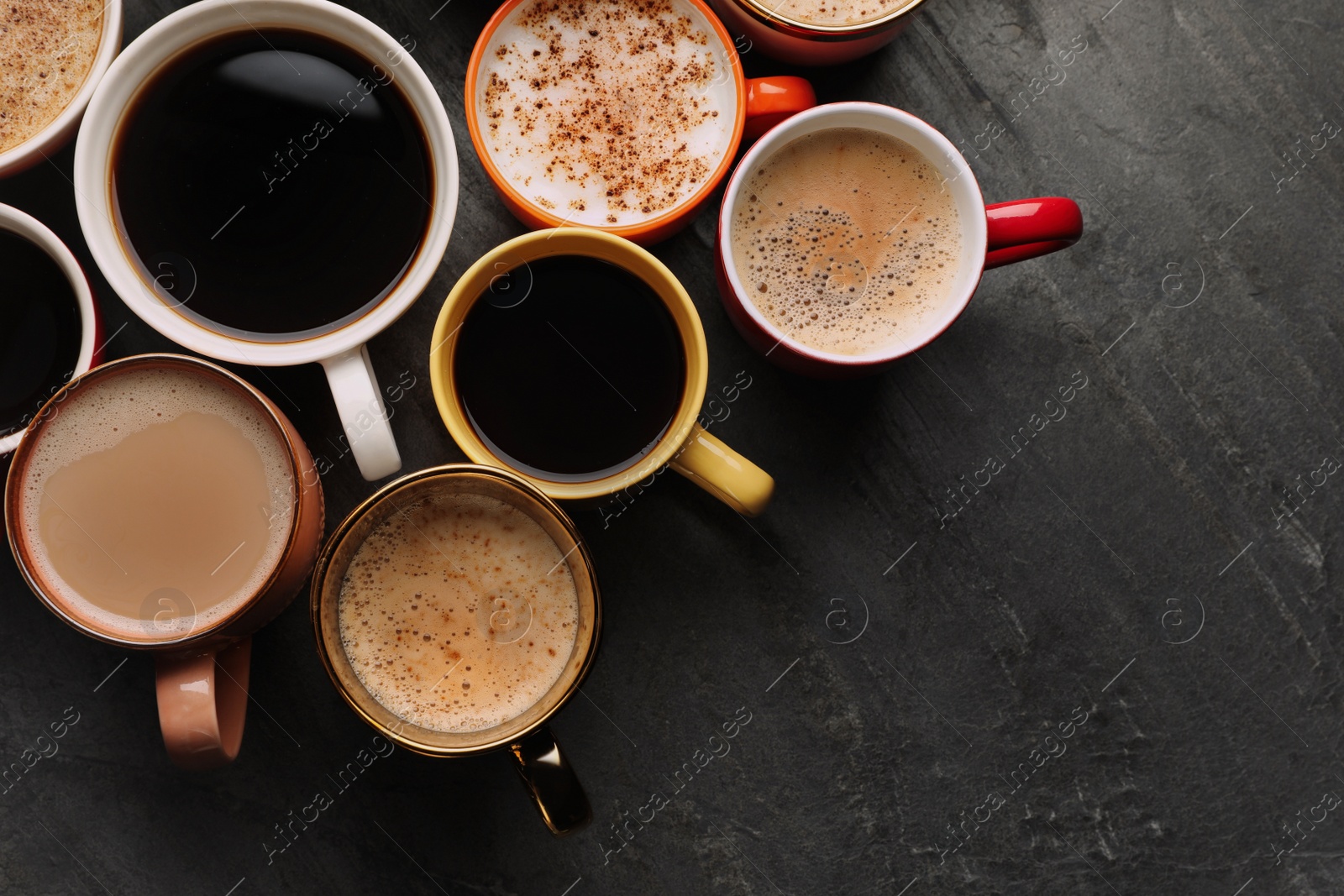 Photo of Many cups of different coffees on slate table, flat lay. Space for text