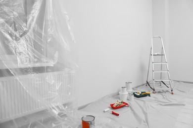 Photo of Metallic folding ladder and painting tools indoors, space for text