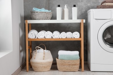 Photo of Many soft terry towels and washing machine in bathroom