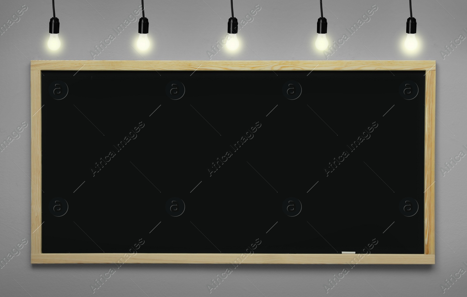 Image of Glowing light bulbs and blackboard hanging on light grey wall