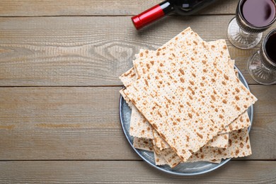 Photo of Stack of traditional matzos and red wine on wooden table, flat lay. Space for text