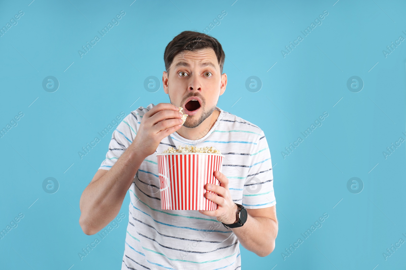 Photo of Emotional man with tasty popcorn on color background