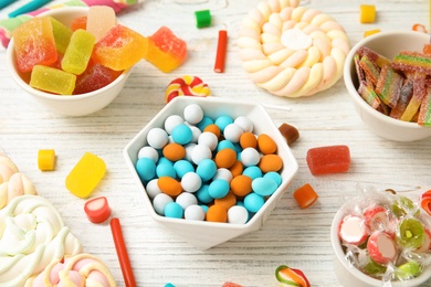 Photo of Composition with different yummy candies on white wooden table