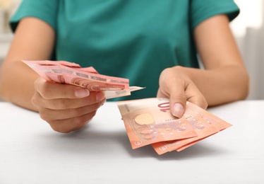 Photo of Woman with Euro banknotes at table indoors, closeup