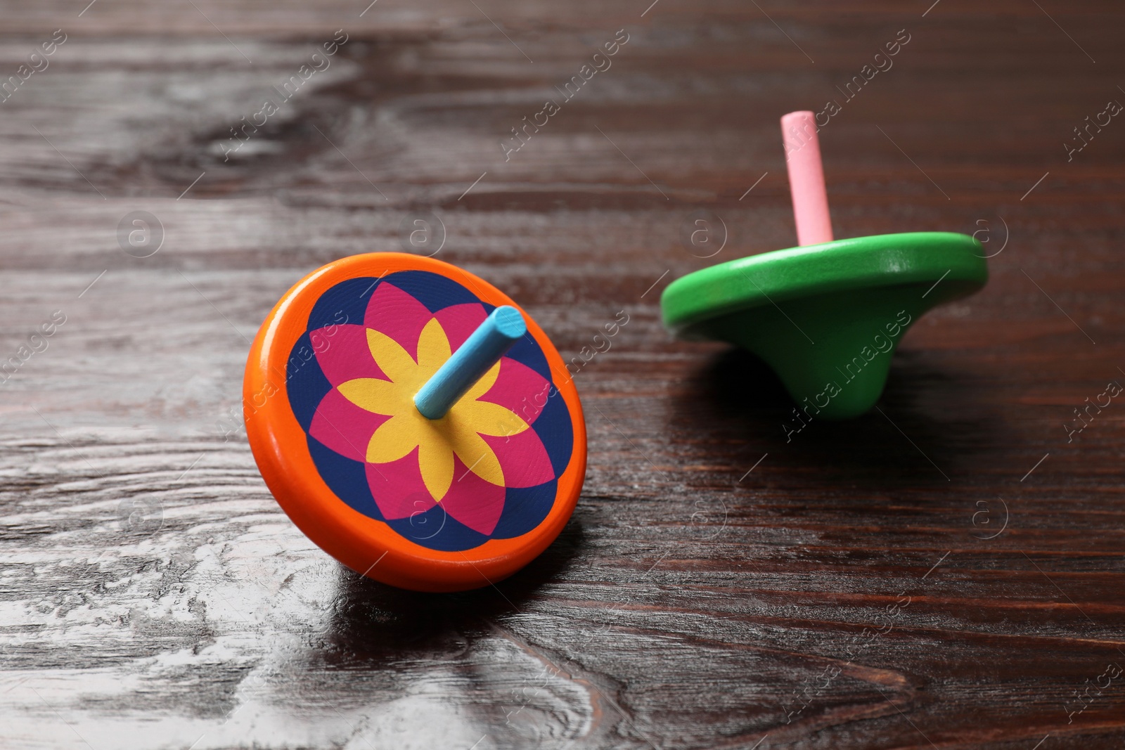 Photo of Bright spinning tops on wooden table, closeup