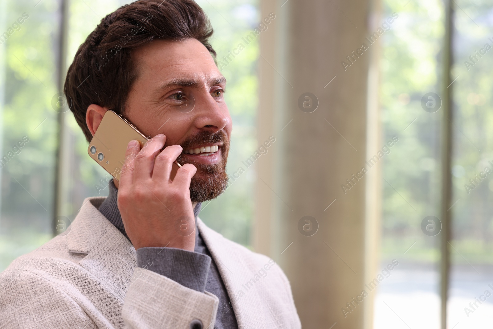 Photo of Handsome man talking on smartphone in office, space for text