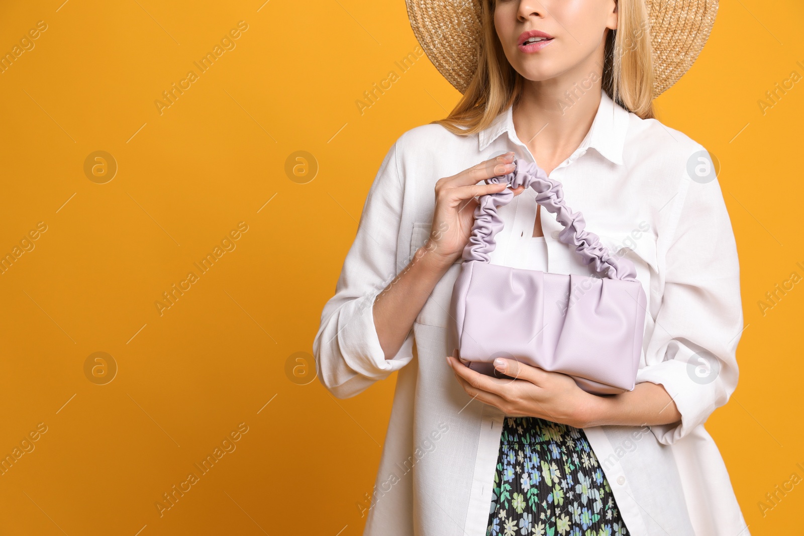 Photo of Stylish woman with trendy baguette bag on yellow background, closeup. Space for text