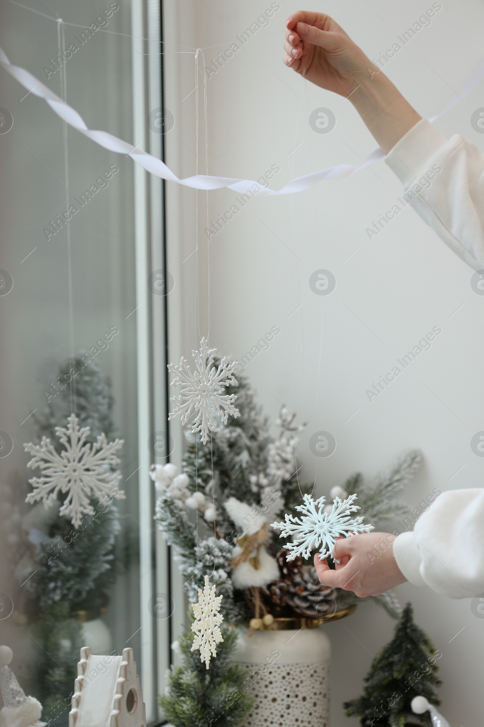 Photo of Woman decorating room for Christmas near window, closeup