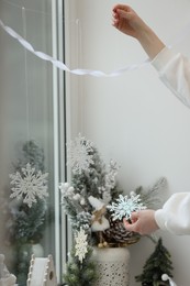 Woman decorating room for Christmas near window, closeup