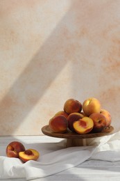 Stand with juicy peaches on white table against beige background