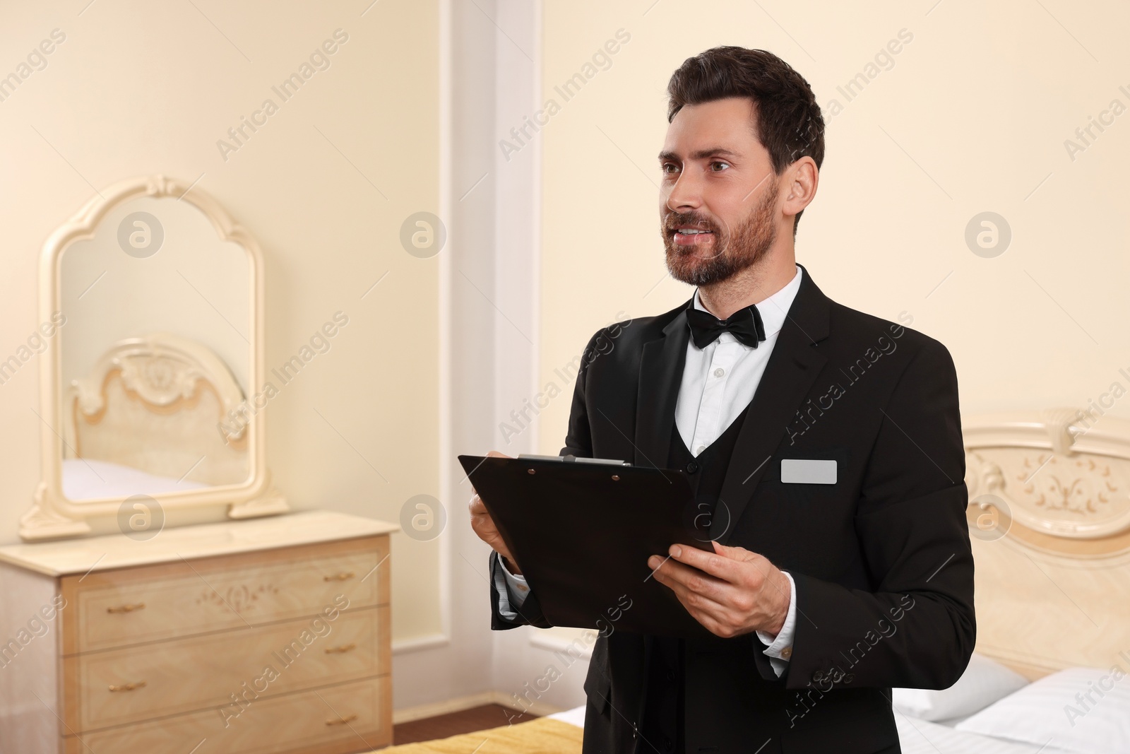 Photo of Man in suit with clipboard indoors, space for text. Professional butler courses