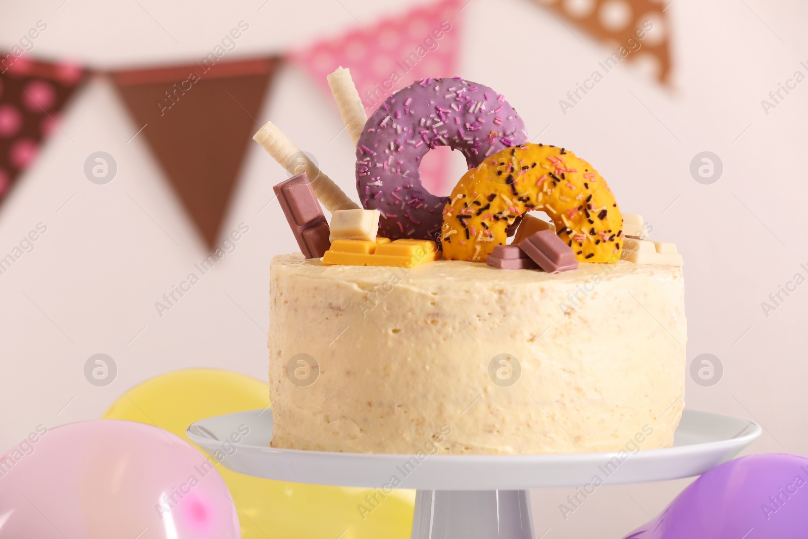 Photo of White stand with delicious cake decorated with sweets against blurred background