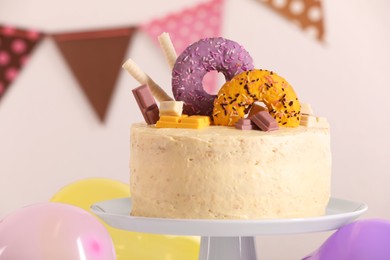Photo of White stand with delicious cake decorated with sweets against blurred background
