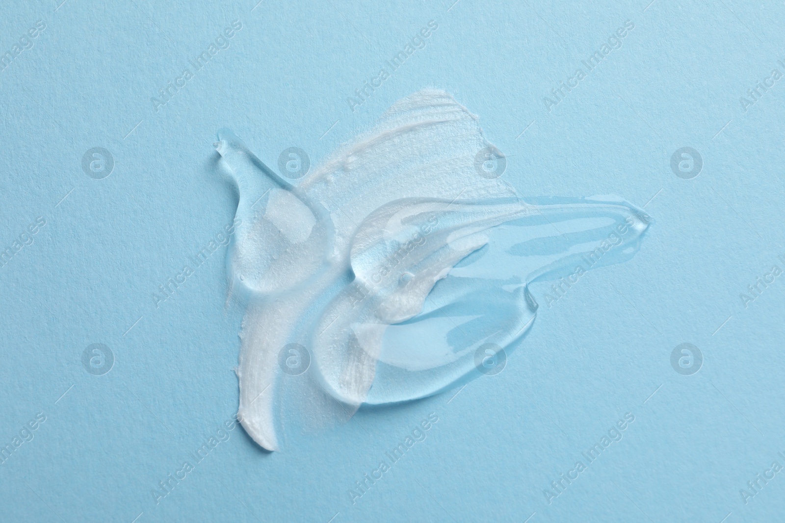 Photo of Samples of cosmetic gel and cream on light blue background, top view