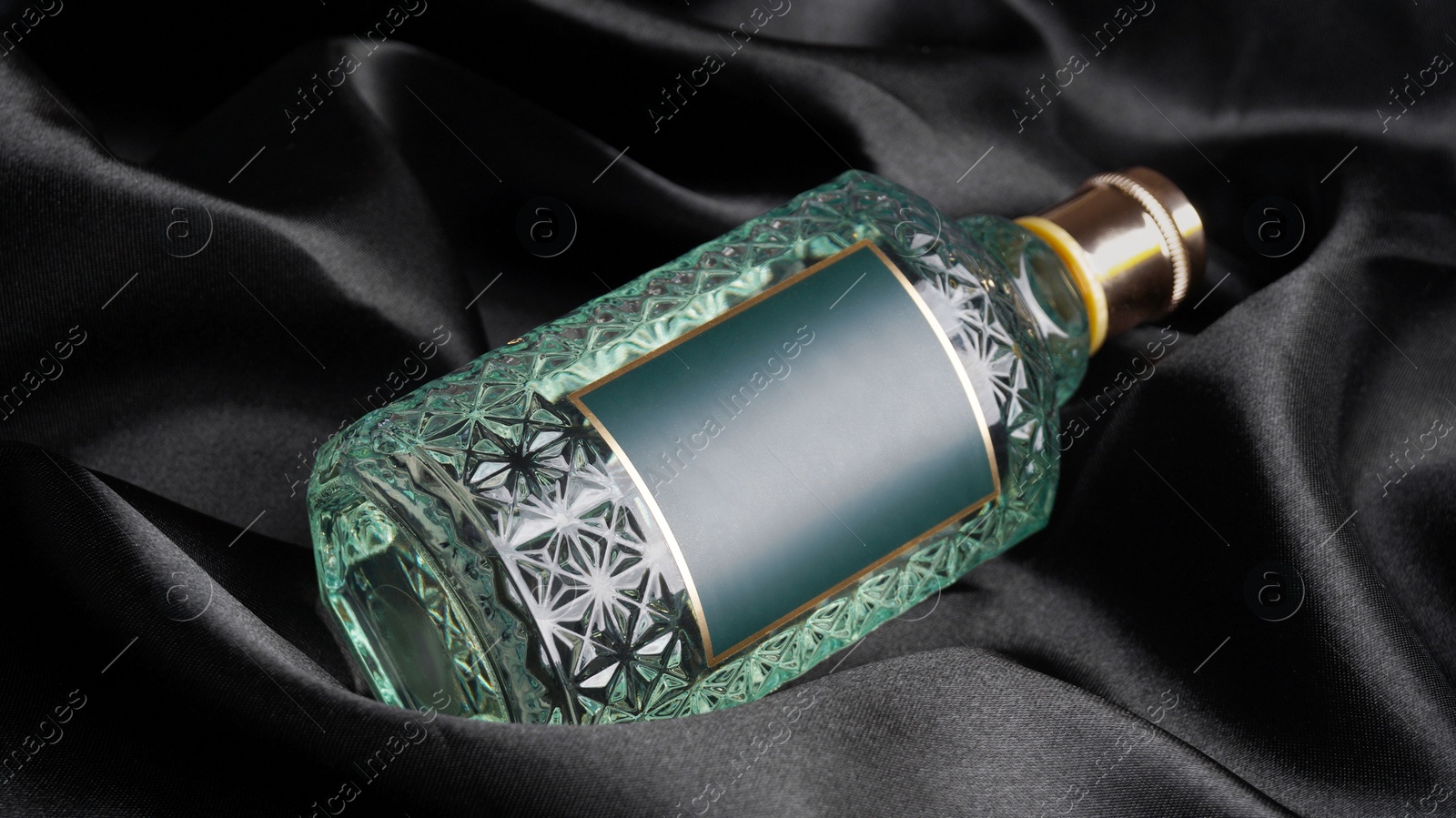 Photo of Luxury bottle of perfume on black silk, closeup