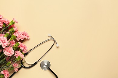 Photo of Stethoscope and beautiful carnation flowers on beige background, flat lay with space for text. Happy Doctor's Day