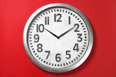 Modern clock on red background, top view