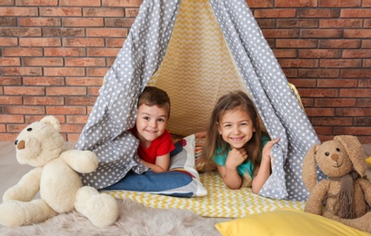 Playful little children in handmade tent indoors