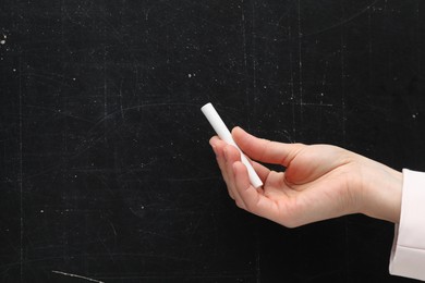 Teacher writing with chalk on black chalkboard, closeup. Space for text