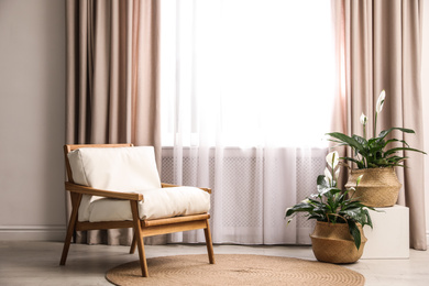 Photo of Comfortable armchair near window with elegant curtains in room