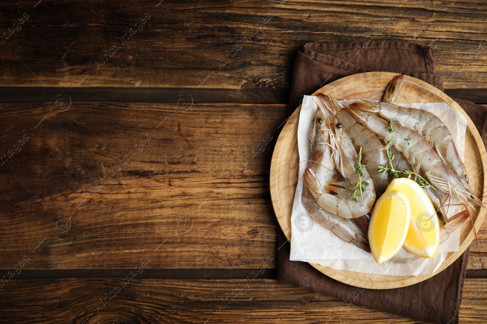 Photo of Fresh raw shrimps with lemon slices on wooden table, top view. Space for text