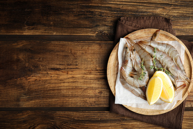 Photo of Fresh raw shrimps with lemon slices on wooden table, top view. Space for text