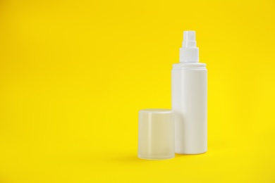 Photo of Bottle with insect repellent spray on yellow background, space for text