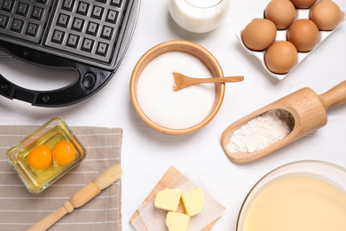 Flat lay composition with ingredients for cooking Belgian waffles on white wooden table