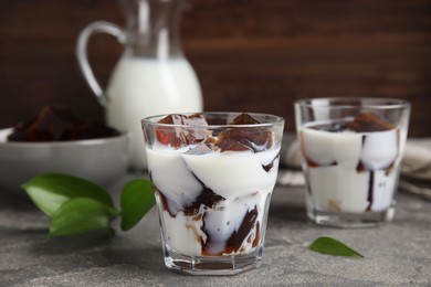 Photo of Glasses of milk with delicious grass jelly on grey table