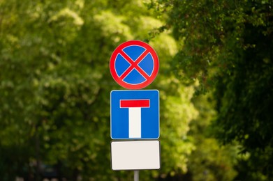 Photo of Post with different traffic signs near trees outdoors