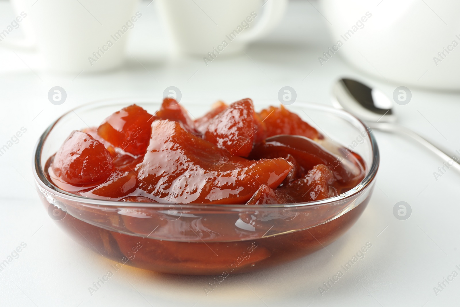 Photo of Quince jam in glass bowl on white table, closeup