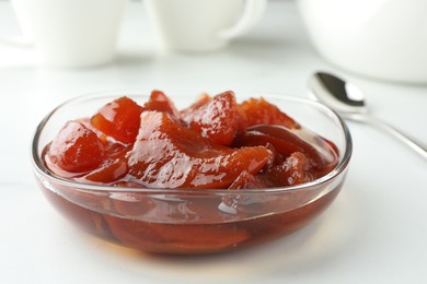 Quince jam in glass bowl on white table, closeup