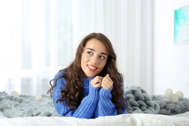 Portrait of young beautiful woman lying on bed at home