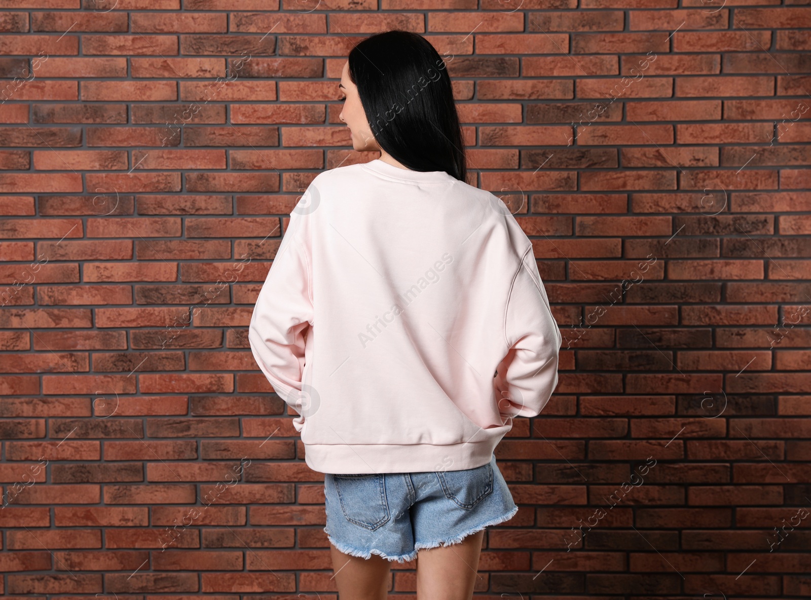 Photo of Young woman in sweater at brick wall. Mock up for design