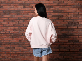 Photo of Young woman in sweater at brick wall. Mock up for design